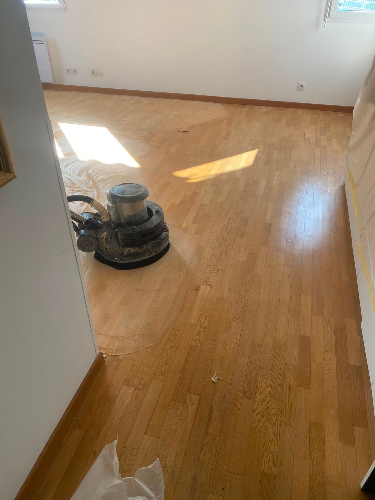 Ponçage du parquet à la ponceuse à bande dans une chambre à Paris 15e