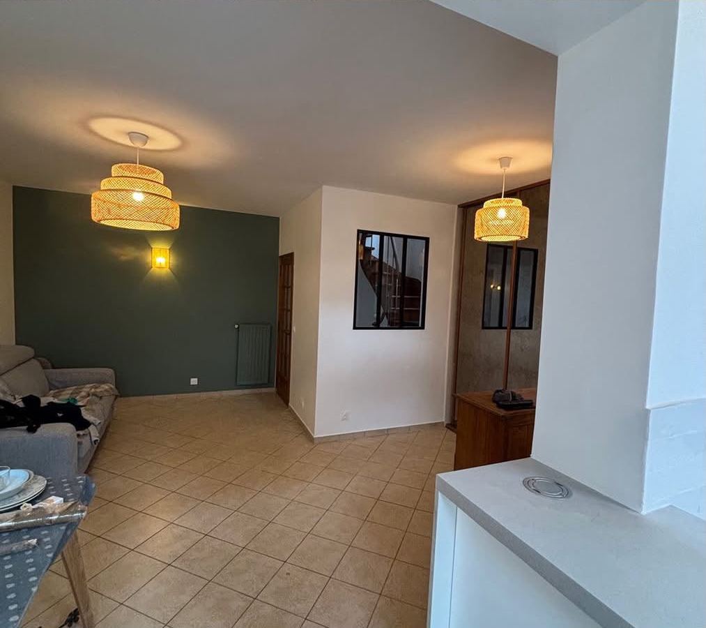 Le même séjour après peinture : mur d'accent vert, plafond repris, nouveaux luminaires