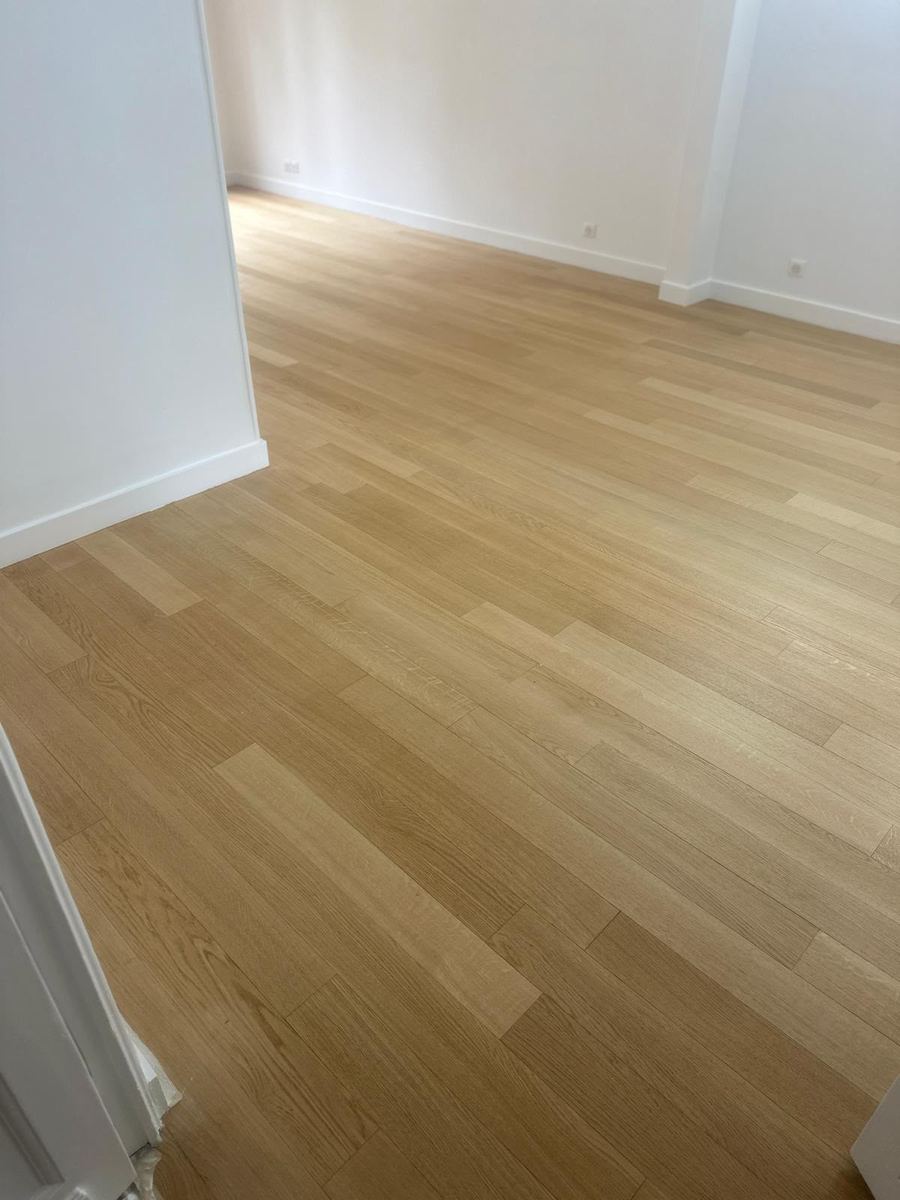 Parquet massif livré : lames alignées et plinthes reprises — Pose de parquet et sols (Fin de chantier) | GLOBAL CONSTRUCTION