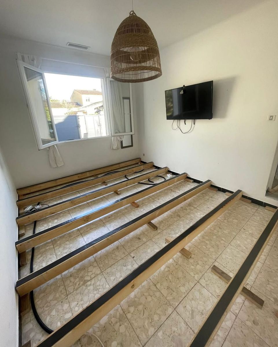 Le plancher déposé : solives dégagées et isolant en cours de mise en place